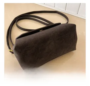 Détail des coutures doubles de précision et de la texture en daim mat d'un sac bandoulière