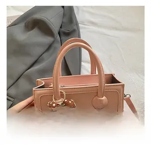 Close-up of pink square handbag with polka dot bear charm and textured leather detail