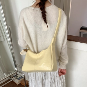 Détails de la texture plissée en similicuir et du charm en peluche sur ce sac jaune
