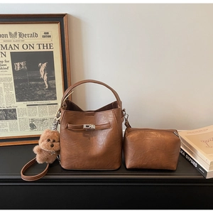 Detailed view of caramel leather bucket bag with silver lock and bear charm