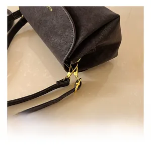 Détail du fermoir mousqueton en métal doré sur un sac en cuir gris foncé mat