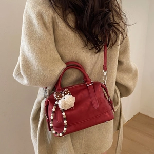 Detail view of vintage red Boston tote bag with plush charm and silver hardware