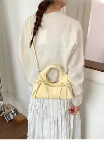 Dettaglio della borsa a mano color crema con fiocchi laterali e tracolla sottile in pelle