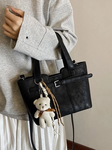 Classic black leather bucket bag with decorative buckle and cute white plush bear pendant