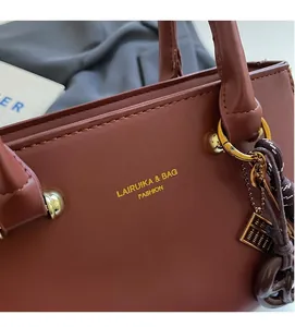Close-up of brown leather bag with gold logo, round hardware and creative abacus charm
