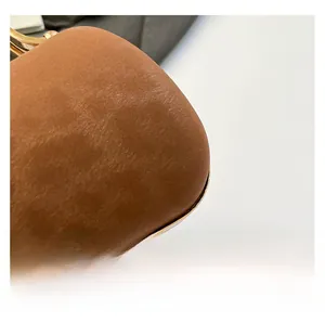 Détail de la texture en cuir marron et du cadre en métal doré d'un sac de soirée chic