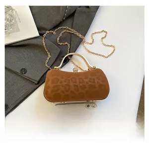 Détail d'un sac de soirée léopard avec poignée dorée et fermoir boule serti de diamants