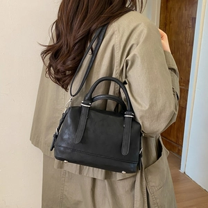Detail view of black leather Boston bag with silver hardware on a model for daily styling