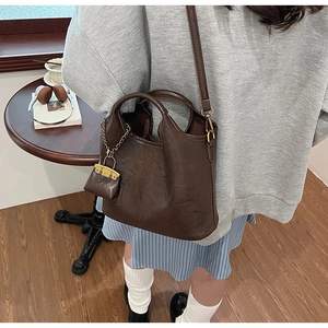 Gros plan du sac seau vintage marron foncé en similicuir avec breloque chaîne dorée