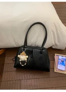 Detail of black vintage pleated handbag with matte leather and cute plush bear charm