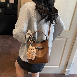 Chic brown leather bucket bag with cute plush puppy charm and pearl accessory