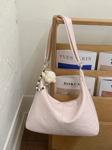 Sac à épaule en cuir verni rose avec texture froissée et pendentif pompon pelucheux