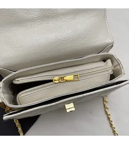 Detail view of white quilted crossbody bag with gold zipper and spacious inner pocket