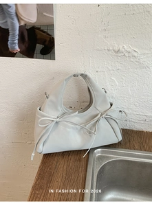 Dettaglio della borsa a mano bianca con fiocchi laterali e manico annodato alla moda