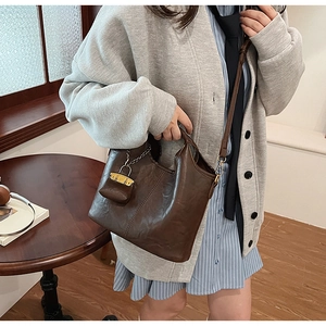 Detail of dark brown leather bucket bag set with contrast stitching and shoulder strap