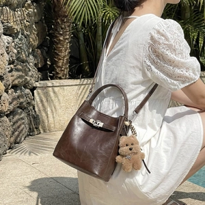 Retro dark brown leather bucket bag with metal turn-lock and cute plush bear charm