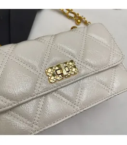 Detailed macro view of the golden metal twist lock and quilted leather on the white bag