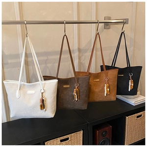 Detail of four large tote bags in suede finish with beaded tassels and metal logo