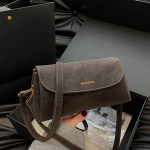Détail d'un sac bandoulière en cuir dépoli taupe foncé avec logo doré et finitions