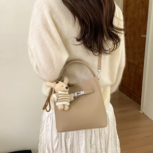 Detail of lychee pattern leather bucket bag with silver lock and plush rabbit charm