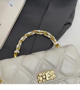 Close-up of quilted cream handbag with woven chain handle and gold rectangle twist lock