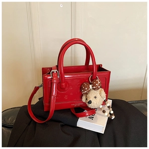 Detail of red patent leather handbag with heart embossing and fluffy bear charm