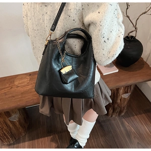 Détail du sac seau vintage noir en cuir texturé avec un pendentif à serrure dorée