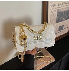 Detailed macro view of white quilted faux leather bag with gold metal chain and twist lock