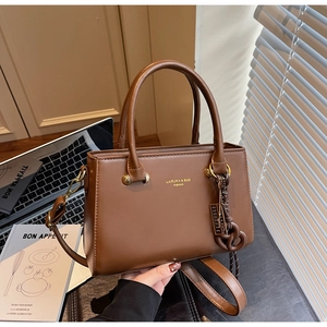 Detailed macro view of matte tan leather handbag with branding and textured handle