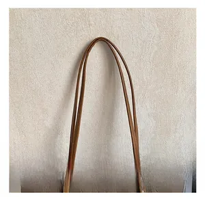 Detail of brown tote bag handle with embossed cartoon puppy texture on high-quality leather