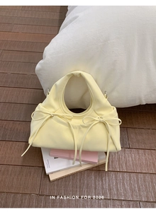 Dettaglio della borsa giallo crema con coulisse a fiocco e manico superiore integrato