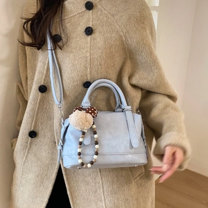 Light blue large capacity PU leather tote bag with plush charm on a model in camel coat