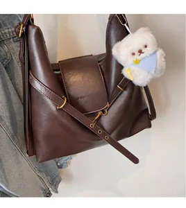 Détail du sac fourre-tout marron foncé avec boucle en métal doré et breloque ours en peluche