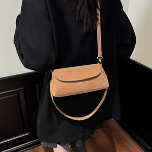 Détail d'un sac bandoulière en daim marron avec sangle réglable porté par un mannequin