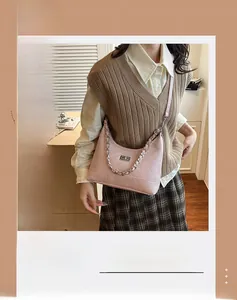 Detail van roze gewatteerde baguette tas met zilveren ketting en metalen draaisluiting