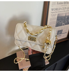 Detail of white quilted leather bag with gold chain strap and adjustable ball ornament