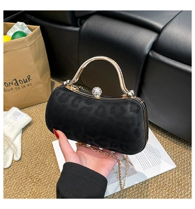 Détail de pochette de soirée léopard noir avec poignée dorée et fermoir diamanté brillant