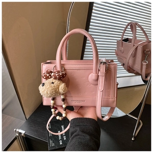 Pink PU leather handbag with embossed patterns, dual handles and plush dog charm accessory