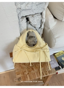 Dettaglio borsa gialla con fiocchi su uno sgabello in un interno dal design minimalista