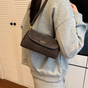 Gros plan sur un sac à bandoulière en daim marron foncé avec logo doré et boucle en métal