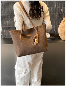 Detail of a brown tote bag with embossed animal patterns and colorful wooden bead charms