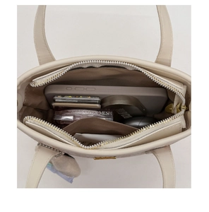 Overhead view showing spacious main compartment of the beige bucket bag with daily essentials