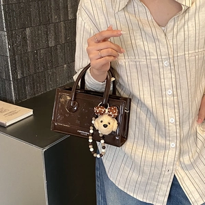 Detailed view of deep brown vintage leather handbag with dog charm accessory