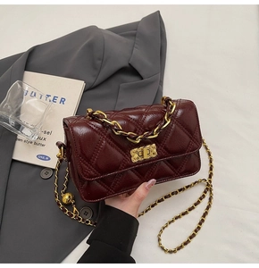 Close-up of burgundy quilted leather handbag with gold chain strap and metal lock