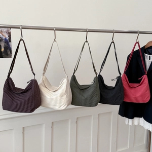 Detail view of crescent crossbody bags in five colors with textured plaid fabric and straps