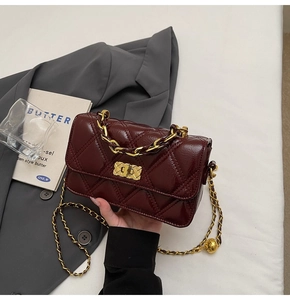 Close-up of wine red quilted diamond pattern shoulder bag with gold chain strap detail
