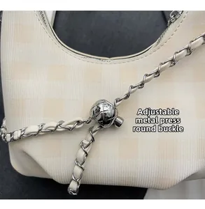 Detail of silver metal press buckle and adjustable chain strap on a plaid hobo bag
