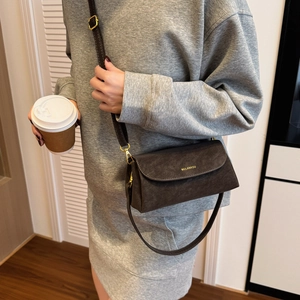 Détail du sac bandoulière marron mat avec logo doré et texture grainée raffinée