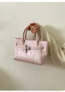 Détail du sac à main en similicuir rose clair avec boucle décorative et anses rondes