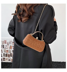 Détail de la pochette léopard avec poignée en strass et chaîne en métal sur un modèle
